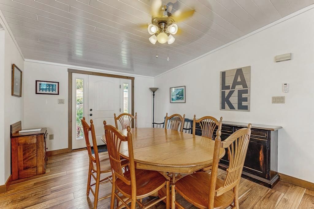 Een eetgedeelte met een houten tafel, stoelen, een plafondventilator en een open haard.