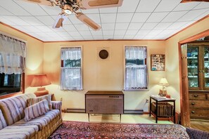 A room with a sofa, a small table, a ceiling fan, and a cabinet. - Classic 2BR Riverfront Adirondacks - Deck (Chestertown)