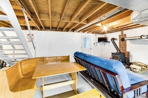 Une table et un banc en bois dans une salle à manger avec des poutres apparentes et une cheminée.