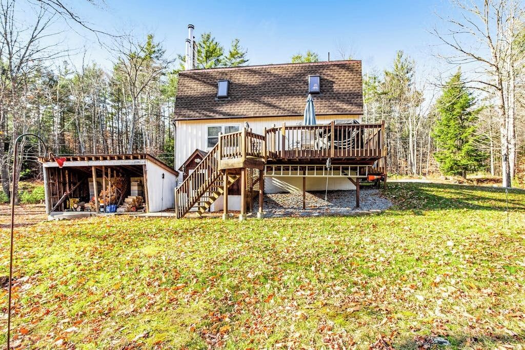 A two-story house with a deck, a covered porch, and a staircase leading to the upper level.