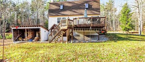 A two-story house with a deck, a covered porch, and a staircase leading to the upper level.