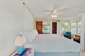 A hotel room with a large bed, a ceiling fan, a window with curtains, and a chair. - Willow Bluff | 3 BR lakefront house with private beach & dock (Keuka Park)