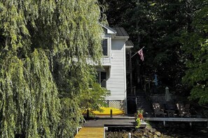 A two-story building with a dock and a yellow kayak. - Willow Bluff | 3 BR lakefront house with private beach & dock (Keuka Park)