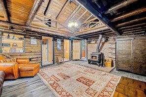 A log cabin interior with a fireplace, leather sofa, and a patterned rug.