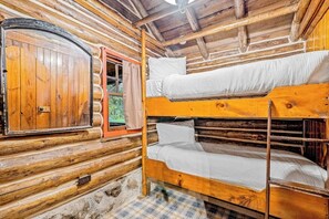 Quarto de cabana de madeira com beliche, porta de madeira e janela.