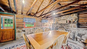 Ein rustikales Holzinnere mit einer Steinwand, einem Holztisch und Stühlen.