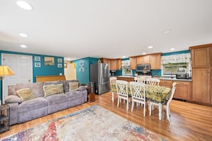 A compact living space with a kitchenette, a sofa, a dining table with chairs, and a patterned rug.