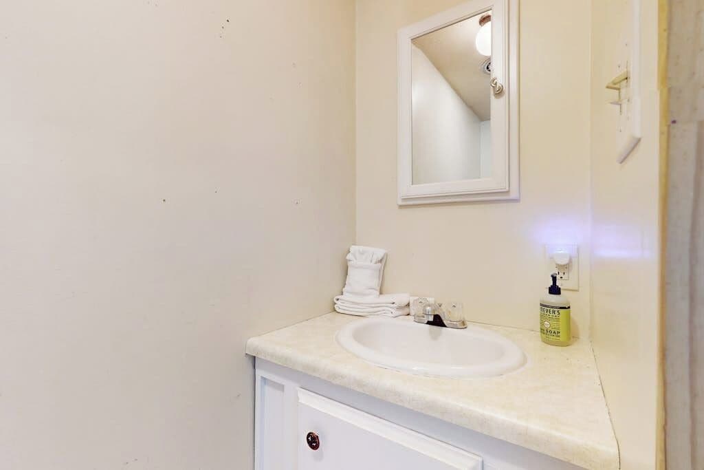 Une salle de bain avec un lavabo blanc, un miroir et une serviette posée sur le comptoir.