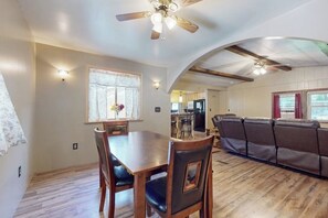 A dining area with a wooden table and chairs, a ceiling fan, and a kitchen in the background. - 3BR Finger Lakes - Deck - Washer Dryer (Penn Yan)