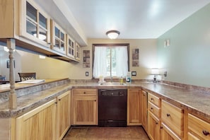 A kitchen with wooden cabinets, a dishwasher, and a window with curtains. - 3BR Finger Lakes - Deck - Washer Dryer (Penn Yan)