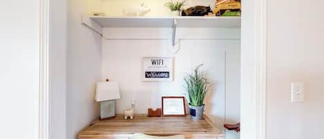 A compact workspace with a desk, chair, and a wall-mounted shelf above.