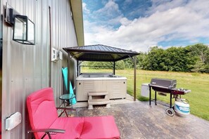 An outdoor patio with a hot tub, grill, and seating area. - Italy Hill Estate | Charming Retreat 2BR Finger Lakes - Hot Tub (Branchport)