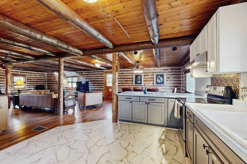 A log cabin interior with a kitchen, dining area, and a living room.