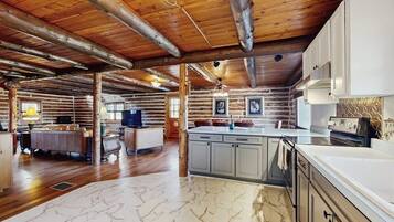 A log cabin interior with a kitchen, dining area, and a living room.