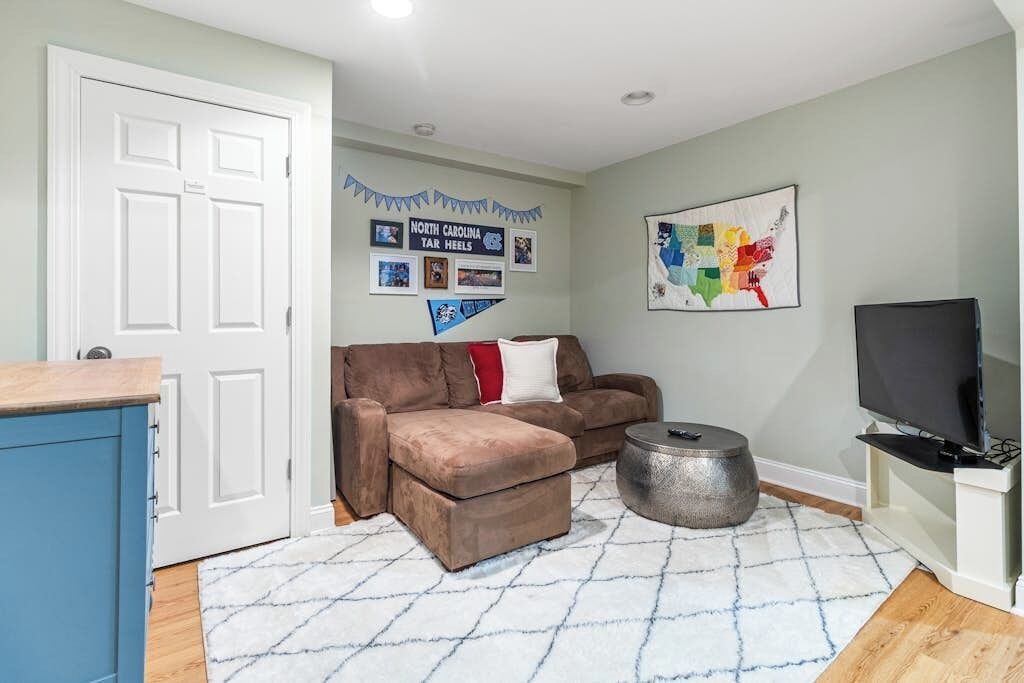 A living room with a brown sofa, a round coffee table, a flat-screen TV, and a wall map.