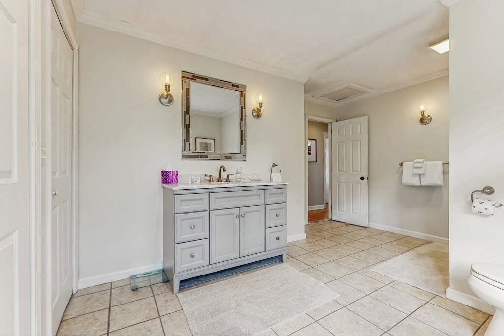 A bathroom with a white vanity, a large mirror, and a toilet.