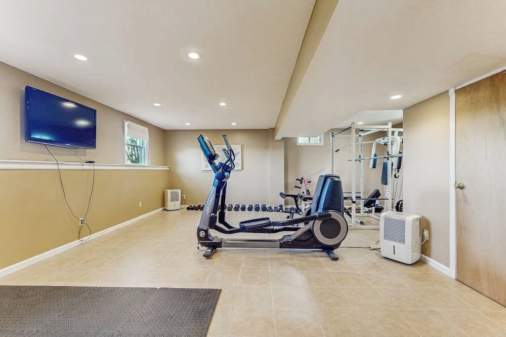 A home gym with exercise equipment, a television, and a window.