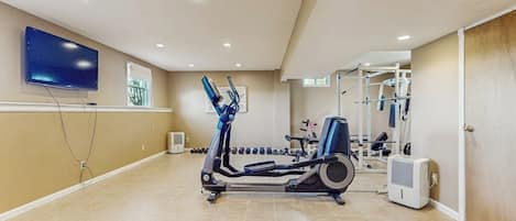 A home gym with exercise equipment, a television, and a window.