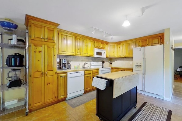 A kitchen with wooden cabinets, a microwave, a refrigerator, and a small island with a sink. - 3BR mountain-view house with fireplace (Thurman)