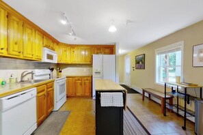 A kitchen with wooden cabinets, a microwave, a refrigerator, and a dining area with a bench. - 3BR mountain-view house with fireplace (Thurman)