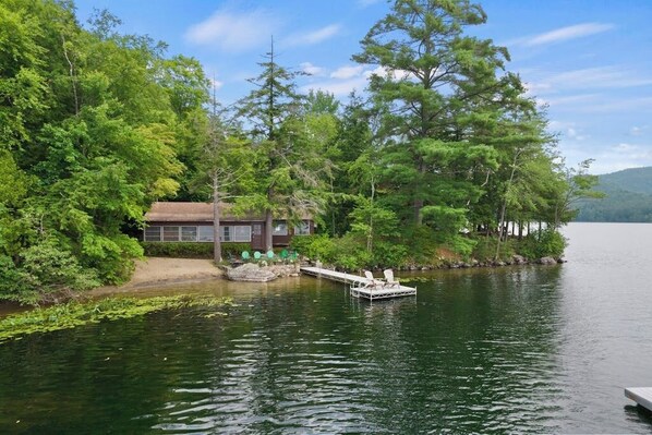 A lakeside cabin with a dock extending into the water, surrounded by dense forest. - Gorgeous 3BR Lakefront Adirondacks - Dock (Brant Lake)