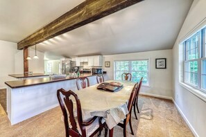 A dining area with a table, chairs, and a kitchen in the background. - Spacious 4BR with firepit & dock, nearby lake access (Chestertown)