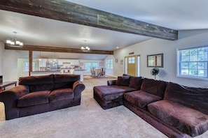 A spacious living room with a large sectional sofa, a dining area, and a kitchen in the background. - Spacious 4BR with firepit & dock, nearby lake access (Chestertown)