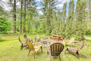 A circular seating arrangement with chairs and a picnic table in a forested area. - Spacious 4BR with firepit & dock, nearby lake access (Chestertown)