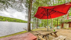 Un espace de pique-nique au bord du lac, avec des bancs en bois et un parasol rouge.