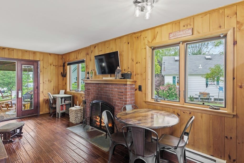 A wooden interior with a fireplace, a round table, and chairs.
