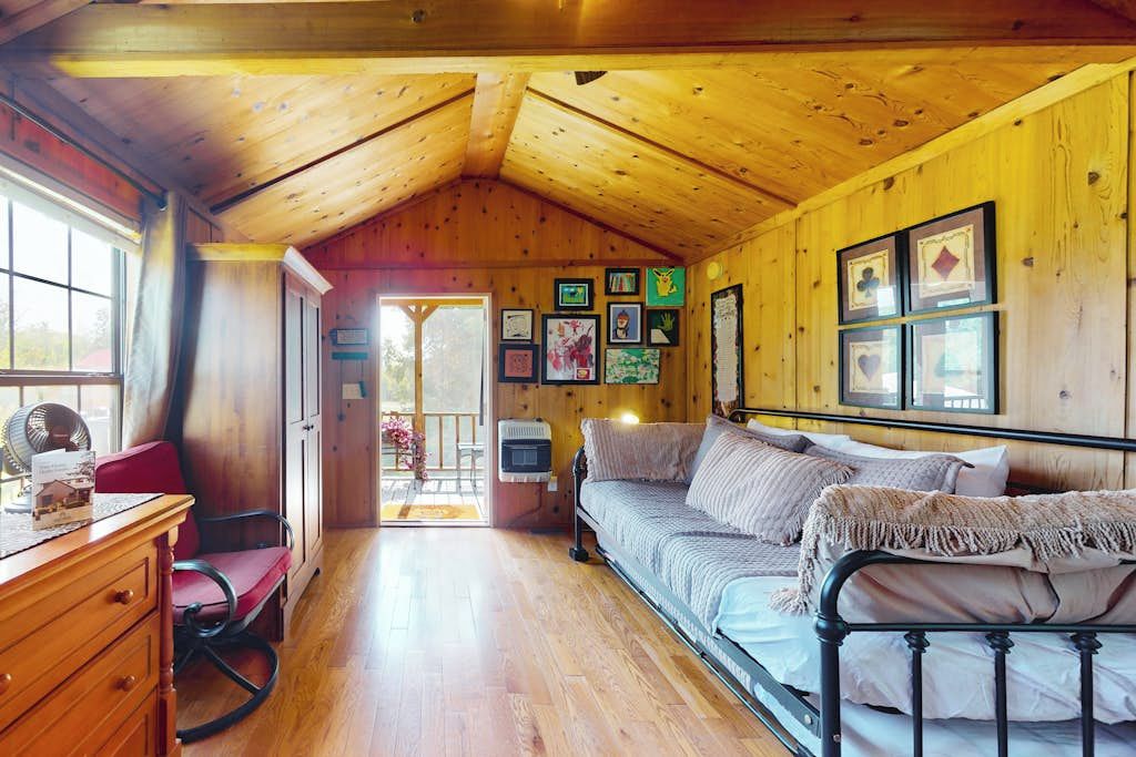 L’intérieur d’un chalet confortable, avec un plafond en bois, un lit, un bureau et une chaise.