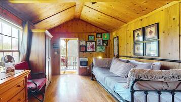 L’intérieur d’un chalet confortable, avec un plafond en bois, un lit, un bureau et une chaise.