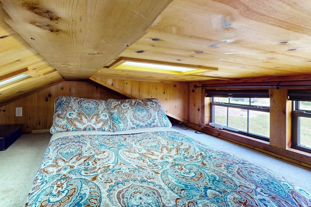Une chambre avec un grand lit, des poutres apparentes en bois au plafond et une fenêtre offrant une belle vue.