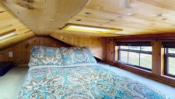 Une chambre avec un grand lit, des poutres apparentes en bois au plafond et une fenêtre offrant une belle vue.