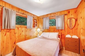 A wooden-paneled bedroom with a bed, a dresser, a mirror, and curtains. - 3BR Lakefront - Fireplace - Dock - Screened Porch (Chestertown)