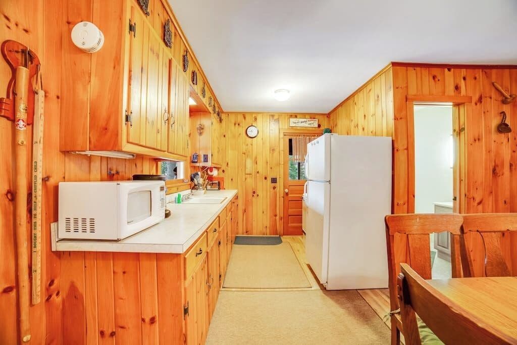 Eine Küche mit Holzvertäfelung, einer Mikrowelle, einem Kühlschrank und Holzschränken.