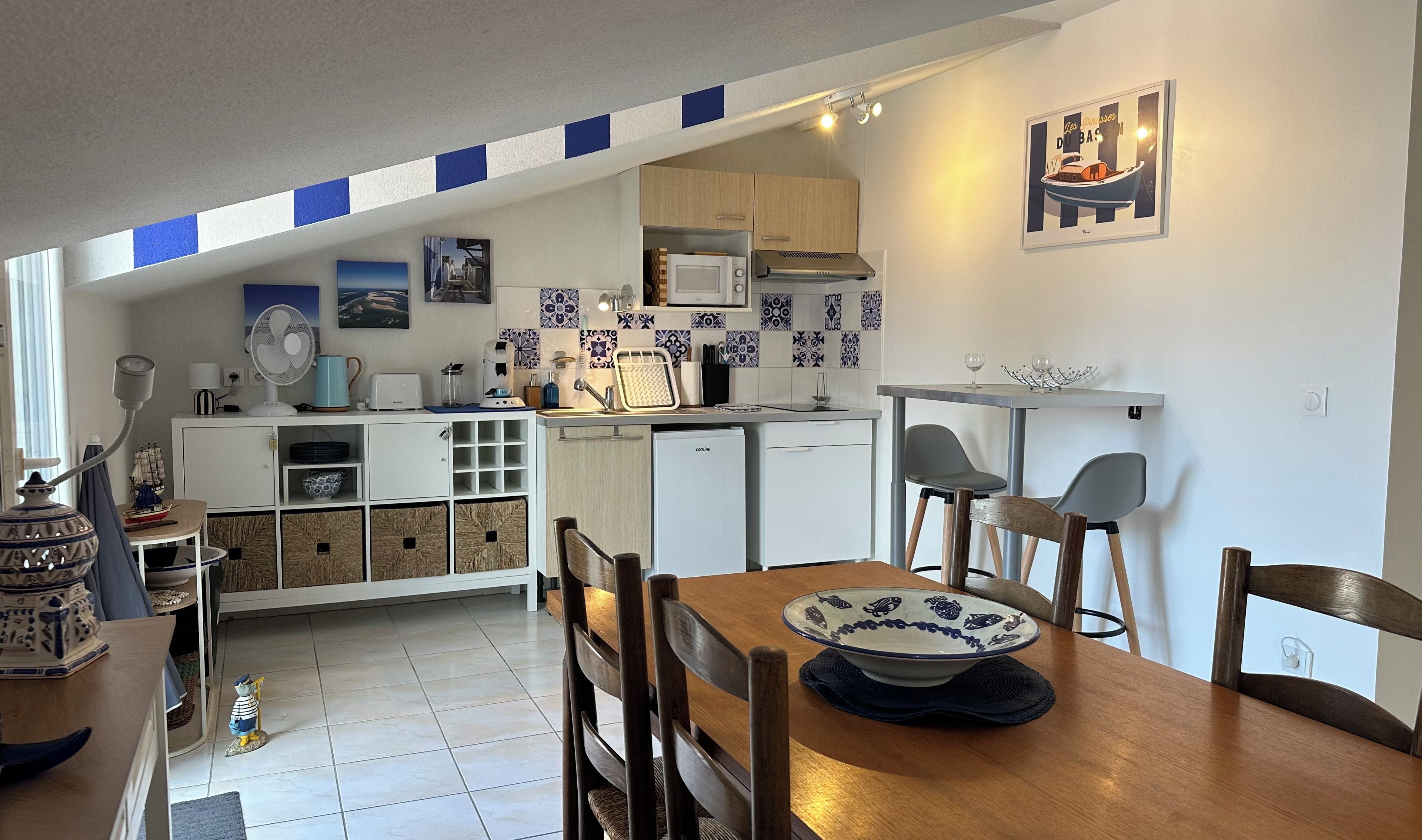 A compact kitchen with a dining area, featuring a microwave, sink, and a small refrigerator.