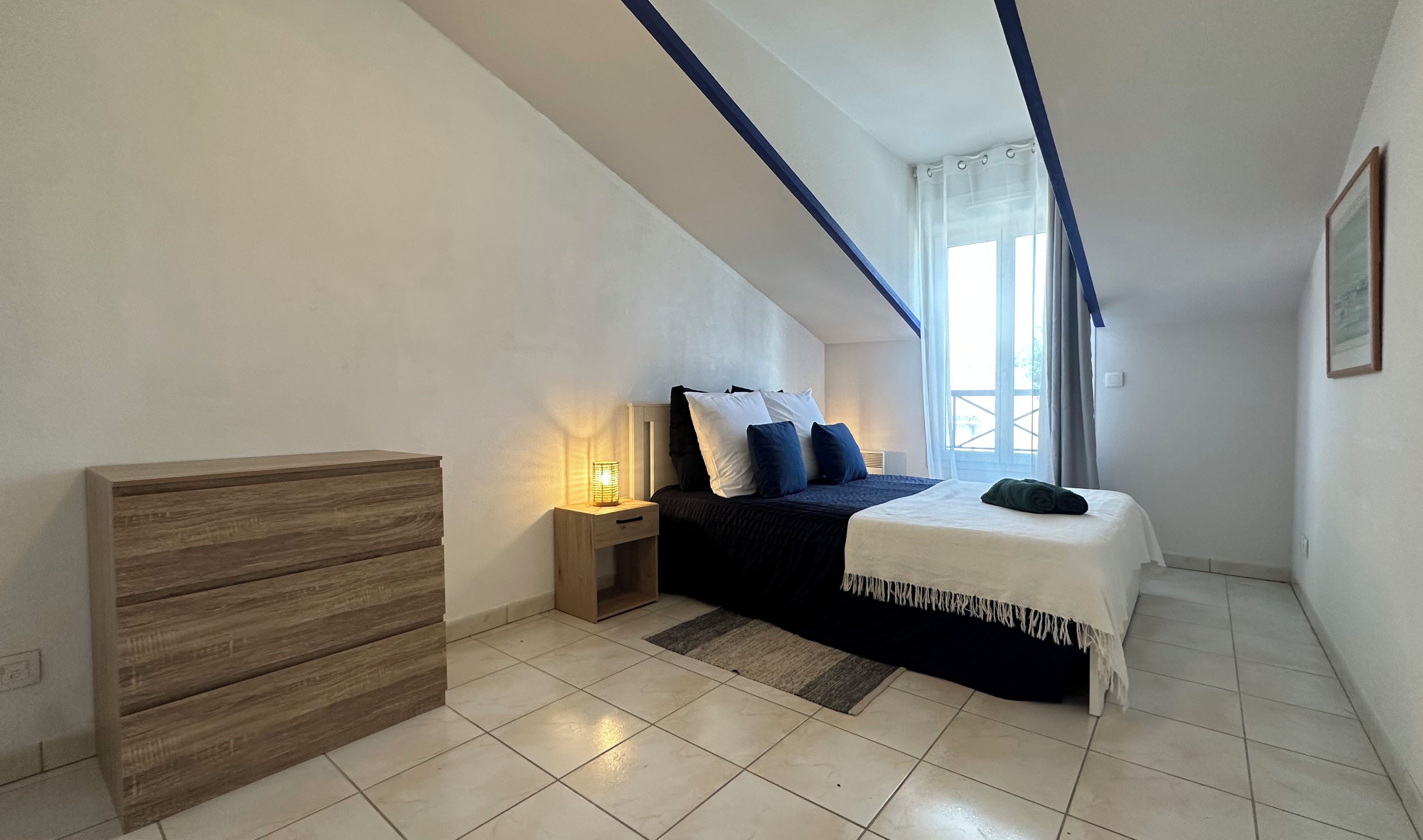 Ein Schlafzimmer mit einem Bett, einem Nachttisch und einer Holzkommode.