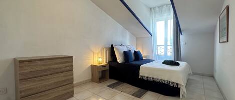A bedroom with a bed, bedside table, and a wooden dresser.