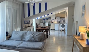 Ein modernes Wohnzimmer mit Sofa, Esstisch und Küchenbereich, inklusive Mikrowelle und Spüle.