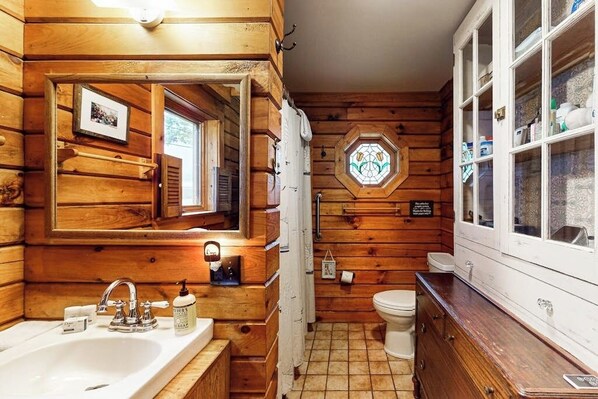 A wooden cabin bathroom with a sink, mirror, and toilet. - 2BR lakefront with hot tub, dock, & 50ft shoreline (Dundee)