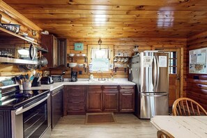 A cabin-style kitchen with wooden walls, a stainless steel refrigerator, and a wooden dining table. - 2BR lakefront with hot tub, dock, & 50ft shoreline (Dundee)