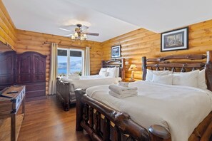 A log cabin-style bedroom with two beds, a ceiling fan, and a window with a view. - 5BR panoramic lake acreage - sauna, game tables (Bolton Landing)