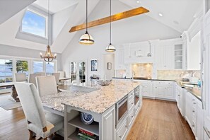 A spacious kitchen with white cabinetry, a large island with a granite countertop, and pendant lighting. - 5BR panoramic lake acreage - sauna, game tables (Bolton Landing)