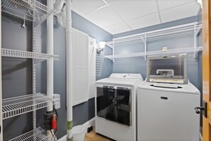 A laundry room with white shelving units, a washing machine, and a dryer. - 5BR panoramic lake acreage - sauna, game tables (Bolton Landing)