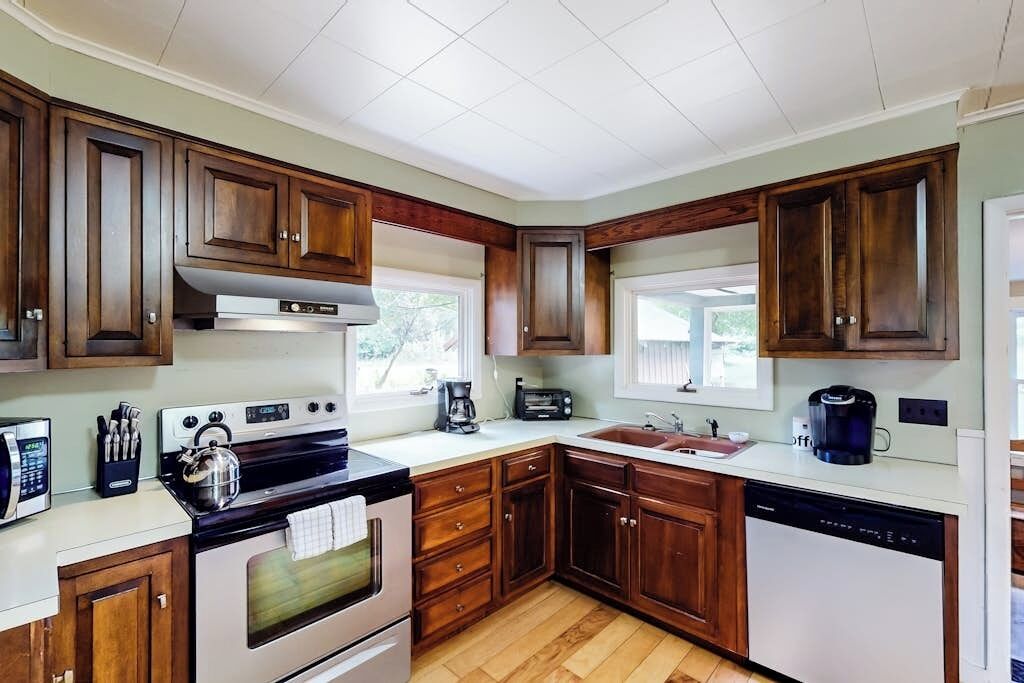 A kitchen with wooden cabinets, a stove, a dishwasher, and a coffee maker.