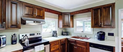 A kitchen with wooden cabinets, a stove, a dishwasher, and a coffee maker.