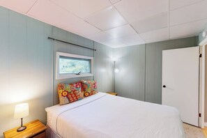 Ein Schlafzimmer mit einem Bett, einer Nachttischlampe, einem Wandbild und einer Tür.