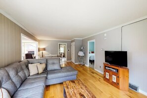 A modern living room with a sectional sofa, a wooden coffee table, and a flat-screen TV on a wooden stand. - 2BR dog friendly cottage with a wood stove (North Creek)
