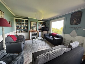 A living room with a fireplace, bookshelves, a sofa, and a coffee table. - Large sea view house near beach & boating (Honfleur)